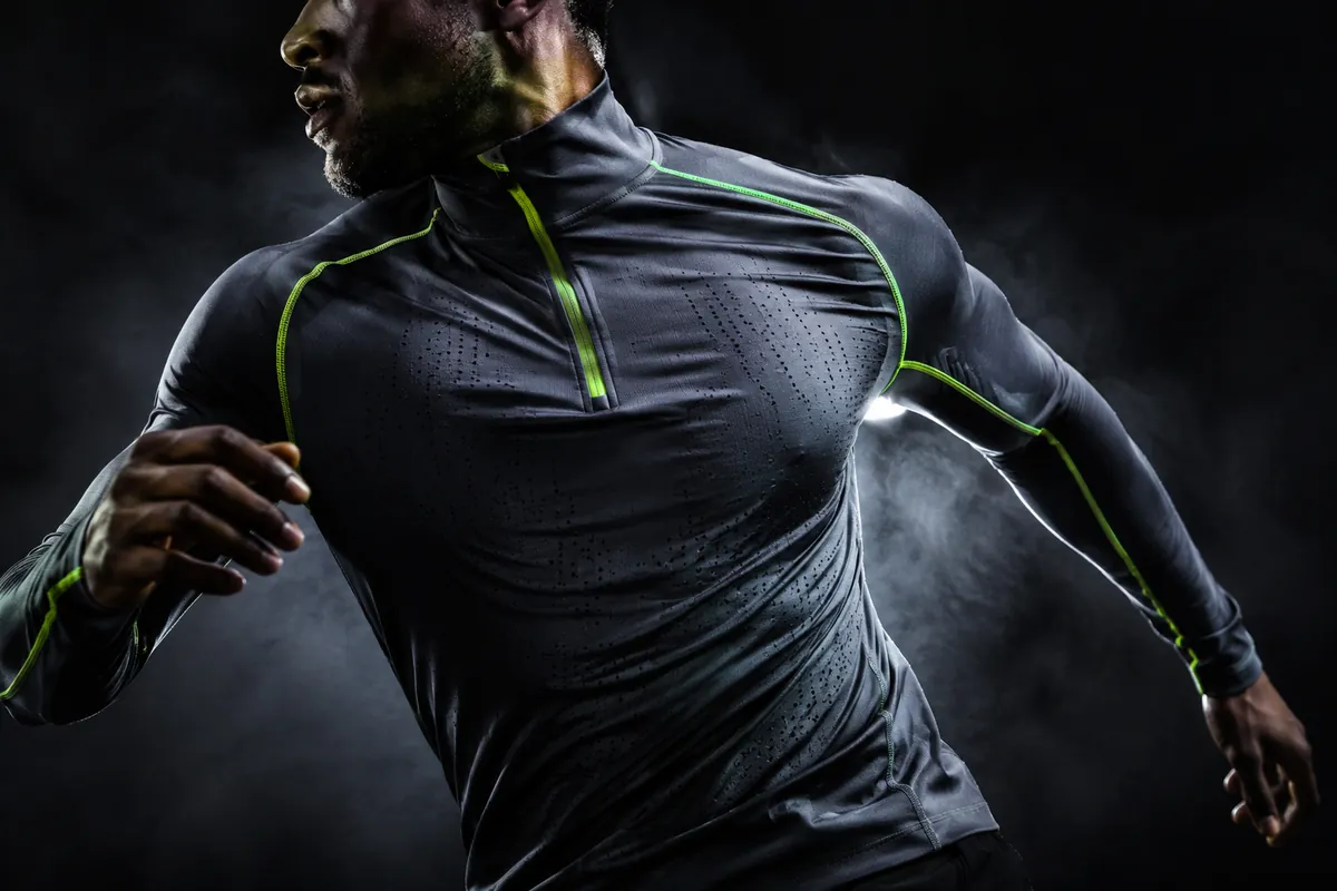 Slipstream Longsleeve — steel-grey quarter-zip longsleeve with volt stitching, shot mid-run